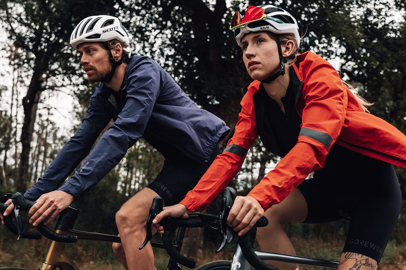 Zwei Radfahrende fahren nebeneinander in sportlicher Kleidung.  
